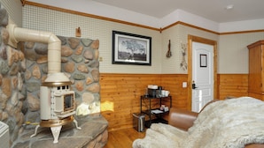 A cozy room with a stone fireplace, wooden walls, a framed picture, and a door.