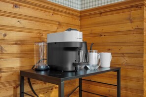 A Nespresso coffee machine on a table with two glasses and a mug.