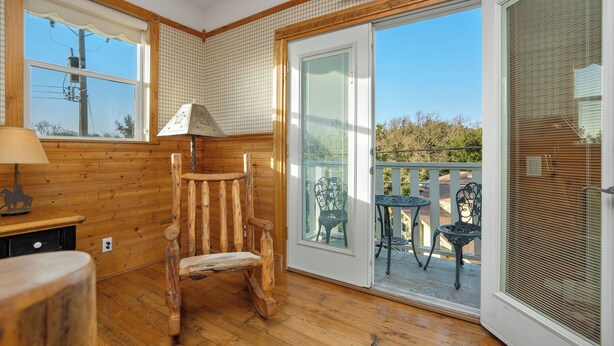 A wooden interior with a rocking chair, a table, and a balcony with chairs.
