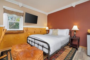 A bedroom with a bed, two bedside lamps, a television, and a window with a curtain.