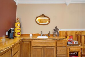 Un comptoir en bois avec un évier, une machine à café et un miroir.