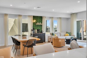 Uma sala moderna com área de jantar, ilha de cozinha e sofá.
