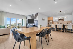 Eine moderne Küche mit Flachbildfernseher, Esstisch aus Holz und schwarzen Stühlen.