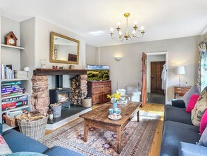 Ein gemütliches Wohnzimmer mit Kamin, Fernseher, Sofa und Couchtisch.
