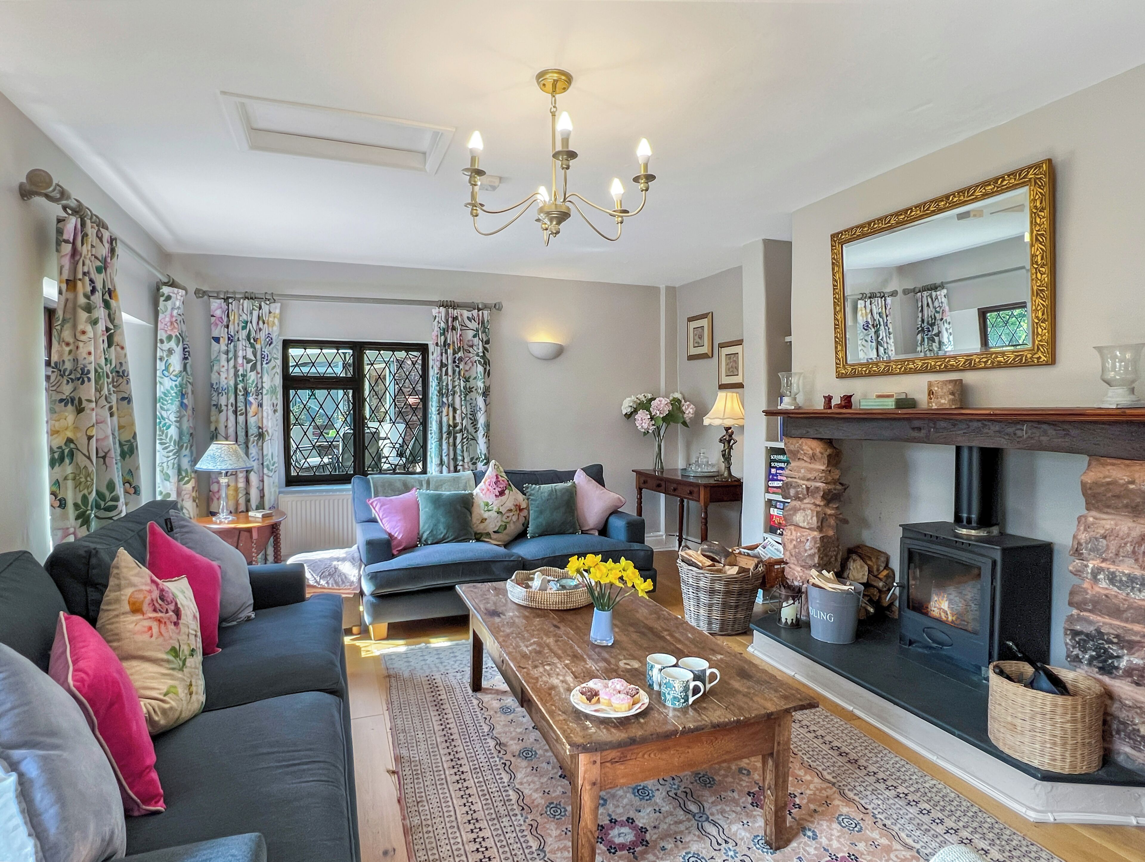 A cozy living room with a sofa, a coffee table, a fireplace, and a large mirror.