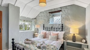 Une chambre à coucher avec un lit, des tables de chevet, des lampes, une fenêtre et une horloge.