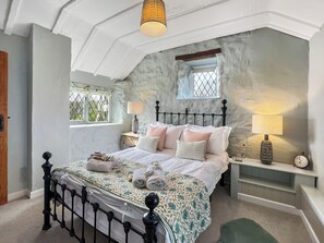 Ein Schlafzimmer mit Bett, Nachttischen, Lampen, einem Fenster und einer Uhr.