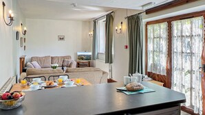 A modern kitchen with a dining area, a sofa, and a TV.