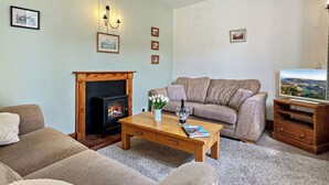 A living room with a fireplace, sofa, coffee table, and television.