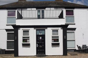 A two-story building with a black door, windows, and a balcony. - Watton By Verve (Thetford)