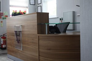 A modern kitchen with wooden cabinets, a glass shelf, and a fire extinguisher. - Watton By Verve (Thetford)