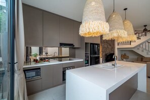 Eine moderne Küche mit einer großen Kochinsel, integrierten Geräten und einer Wand mit Naturstein-Akzenten.