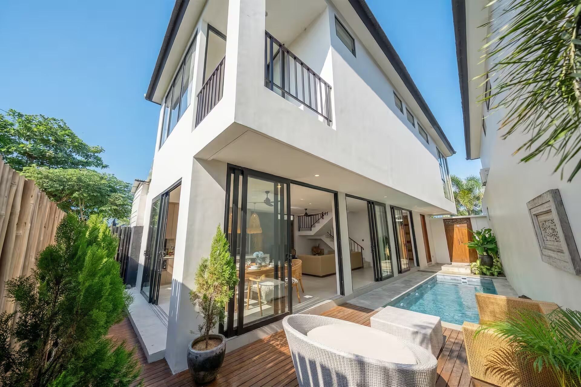 A modern two-story house with a swimming pool, glass doors, and a wooden deck.