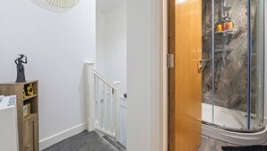 Ein Badezimmer mit Dusche, einem Holzschrank, einer weißen Wand und einem Spiegel.