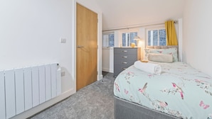 Ein Schlafzimmer mit Bett, Kommode, Heizkörper und einem fenster mit Vorhängen.