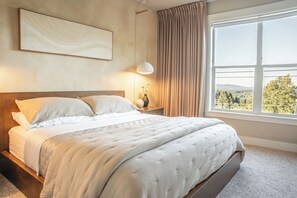 A bedroom with a bed, a bedside table with a lamp, a window with curtains, and a wall-mounted artwork. - “Cooper Mtn Retreat• Chef Kitchen • Mt. Hood View • Sleep 6 • Nike & Intel” (Beaverton)