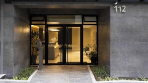A modern building entrance with a reception desk, glass doors, and a number '112' sign.