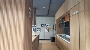 A modern kitchen with wooden cabinets, a black countertop, and a sink. There are framed pictures on the wall and a potted plant.