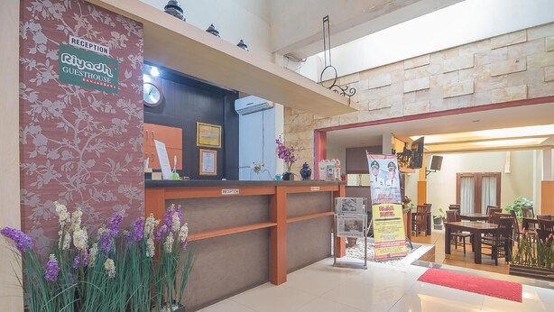 A reception area with a reception desk, a clock, a framed certificate, and a poster. - Formerly Reddoorz Syariah Plus @ Banjarbaru 2 (Banjarbaru)