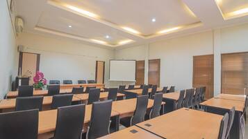 A conference room with multiple tables, chairs, a whiteboard, and a projector screen.