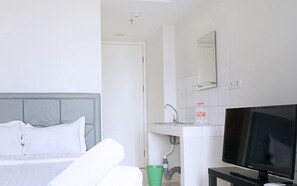 A hotel room with a bed, a TV, a sink, and a mirror. - Springlake Apartment Summarecon by Veeroom by Zuzu (Bekasi)