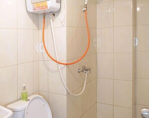 A bathroom with a toilet, a bidet, and a shower with a hose. - Springlake Apartment Summarecon by Veeroom by Zuzu (Bekasi)