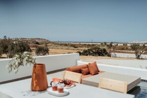 A terrace with a white table, a vase, and a cushion. - Lefteris Studios (Naxos)