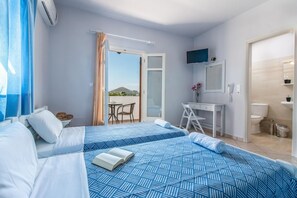 A hotel room with two beds, a desk, a chair, a TV, and a bathroom. - Lefteris Studios (Naxos)