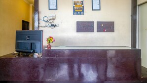 A reception desk with a computer monitor, a flower vase, and framed certificates on the wall.