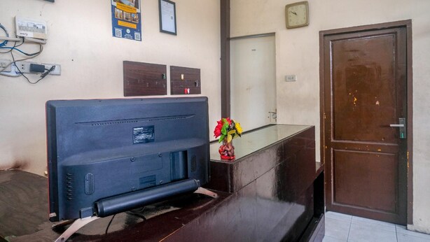 A reception desk with a television, wall-mounted electrical outlets, a clock, and a door.