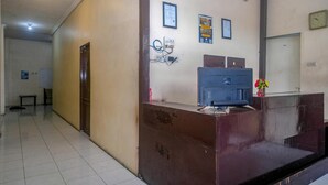 A reception area with a desk, wall-mounted electrical outlets, framed certificates, and a clock.
