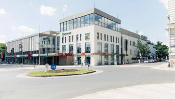A modern building with large glass windows, a central entrance, and signage for 'Cartridge,' 'Harry's,' and 'KULT.'
