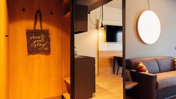 Ein modernes Interieur mit einer Holzwand, einer braunen Stofftasche, einem Sofa, einem Fernseher und einer runden Leuchte.