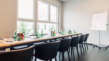 Ein Konferenzraum mit einem langen Tisch, Stühlen und einer Whiteboard-Wand.