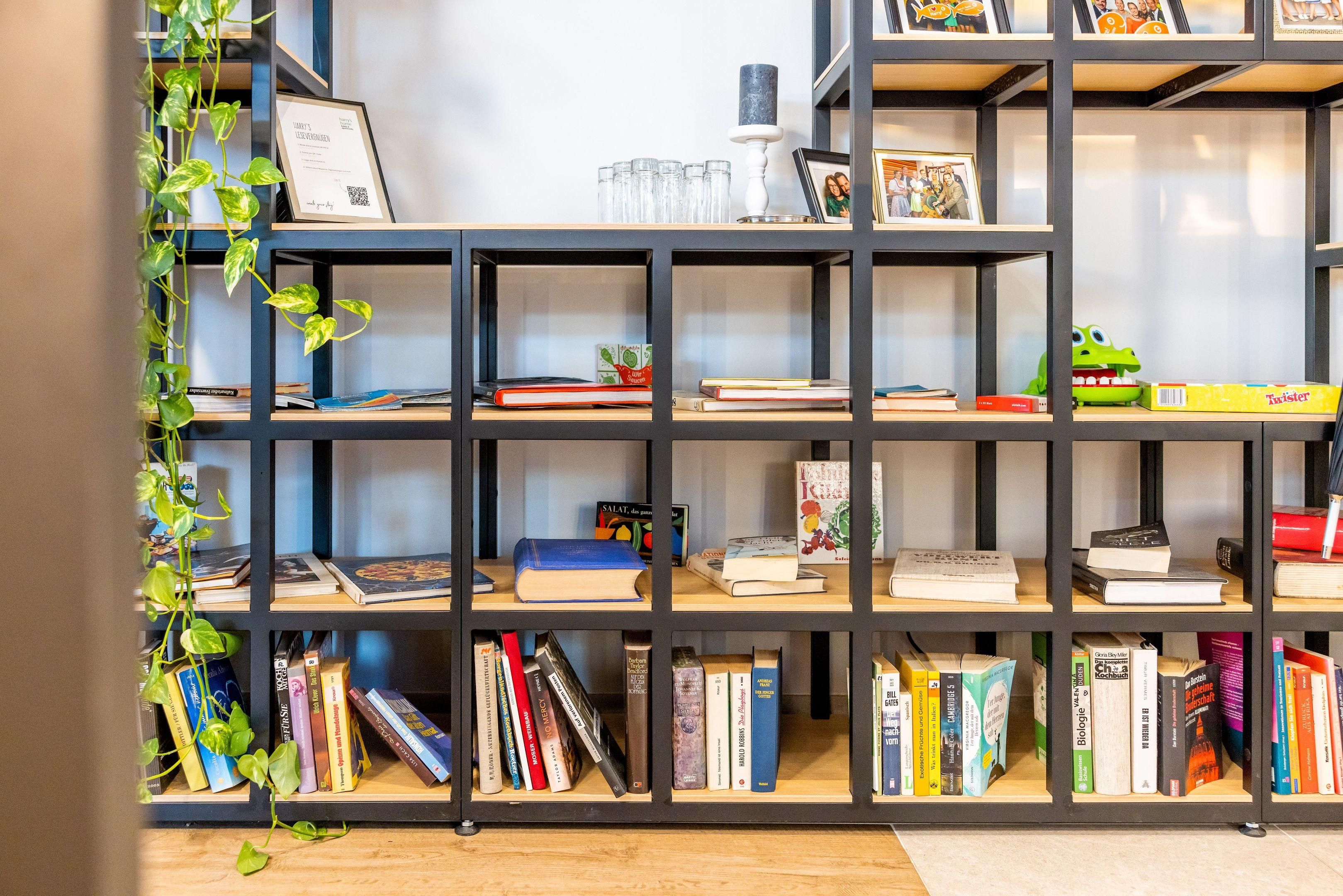 A bookshelf with books, a framed certificate, and a small plant.