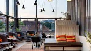 Un interior moderno con una zona de estar, mesas y ventanas amplias que ofrecen vistas de la ciudad.