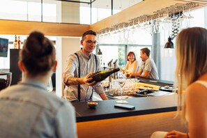 A bar area with a bartender, glasses, and a wine bottle.