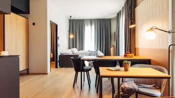 Ein modernes Hotelzimmer mit Essbereich, einer Couch, einem Schreibtisch und einer Lampe.