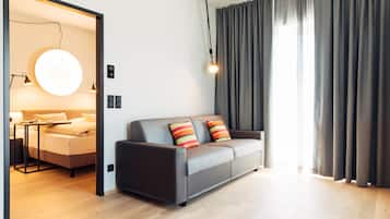 Ein modernes Wohnzimmer mit einem grauen Sofa, einer runden Lampe und Blick durch eine Tür.