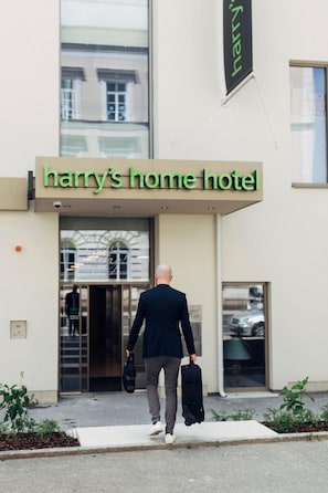 A man walking towards a hotel entrance with a sign reading 'Harry's Home Hotel.' - Harry's Home Steyr Hotel (Alberndorf in der Riedmark)