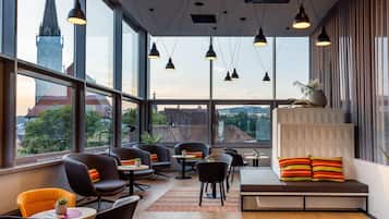 A modern interior with large windows, multiple seating areas, and a view of a cityscape.