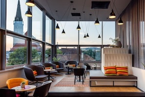 Un interior moderno con ventanas amplias, varias zonas de estar y vistas a un paisaje urbano.