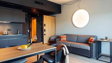 A modern living space with a dining area, sofa, and a wall-mounted light fixture.