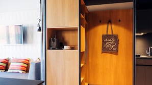 Una habitación moderna con una cama, un escritorio, una cafetera, un hervidor y un bolso colgado en la pared con una cita motivacional.