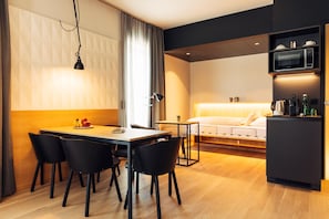 A modern hotel room with a dining area, a bed, and a kitchenette. - Harry's Home Steyr Hotel (Alberndorf in der Riedmark)
