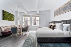 A modern bedroom with a bed, a sofa, a dining table, and chairs. - Sonder City Hall Park (New York)