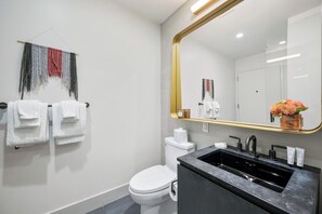 A modern bathroom with a toilet, sink, and mirror. - Sonder City Hall Park (New York)