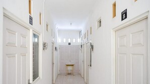 Un pasillo estrecho con puertas blancas, letreros numerados y una pequeña mesa en el centro.