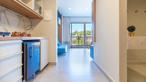 A modern kitchen with a built-in oven and a dining area with a blue chair. - Conforto no île de Pipa por Carpediem (Tibau do Sul)