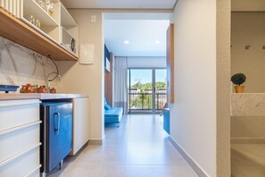 A modern kitchen with a built-in oven and a dining area with a blue chair. - Conforto no Ã®le de Pipa por Carpediem (Tibau do Sul)